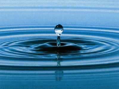 Das Bild zeigt einen Wassertropfen, der in eine Wasserfläche fällt und zurückspringt.