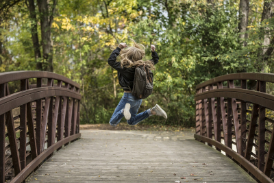 Kind auf einer Brücke das in die Höhe springt.