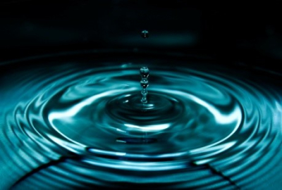 Das Bild zeigt einen Wassertropfen, der in eine Wasserfläche fällt und zurückspringt.
