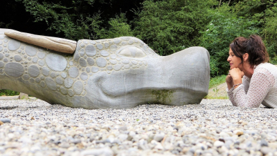 Frau schaut einen grossen, liebevollen Steindrachen an.